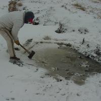 Breaking up frozen watering source using an ax