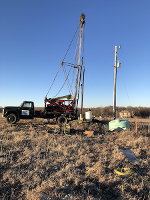 A truck with a drilling rig works to drill a new well on private land.