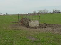 Concrete waterer with soil mound, fenced to prevent livestock from climbing