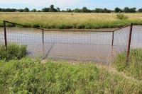 a closer view of a fence that limits livestock access to a pond