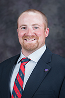 A.J. Tarpoff, in a red and blue striped tie, smiles at the camera