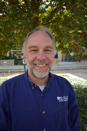 Will Boyer, wearing a purple button-down shirt, smiles at the camera