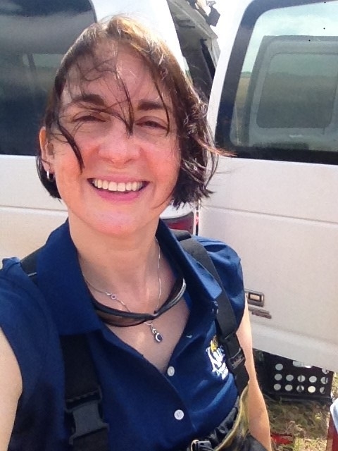 Elizabeth Smith smiles in front of a white vehicle on a windy day