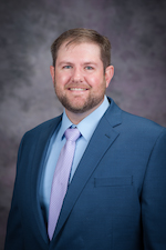 Scott Fritz, in a jacket and tie, smiles at the camera